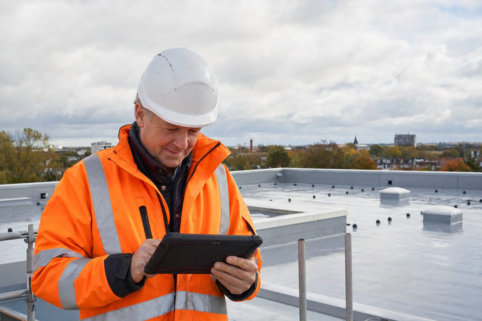 A site supervisor on a flat roof checking quantities on a tablet.